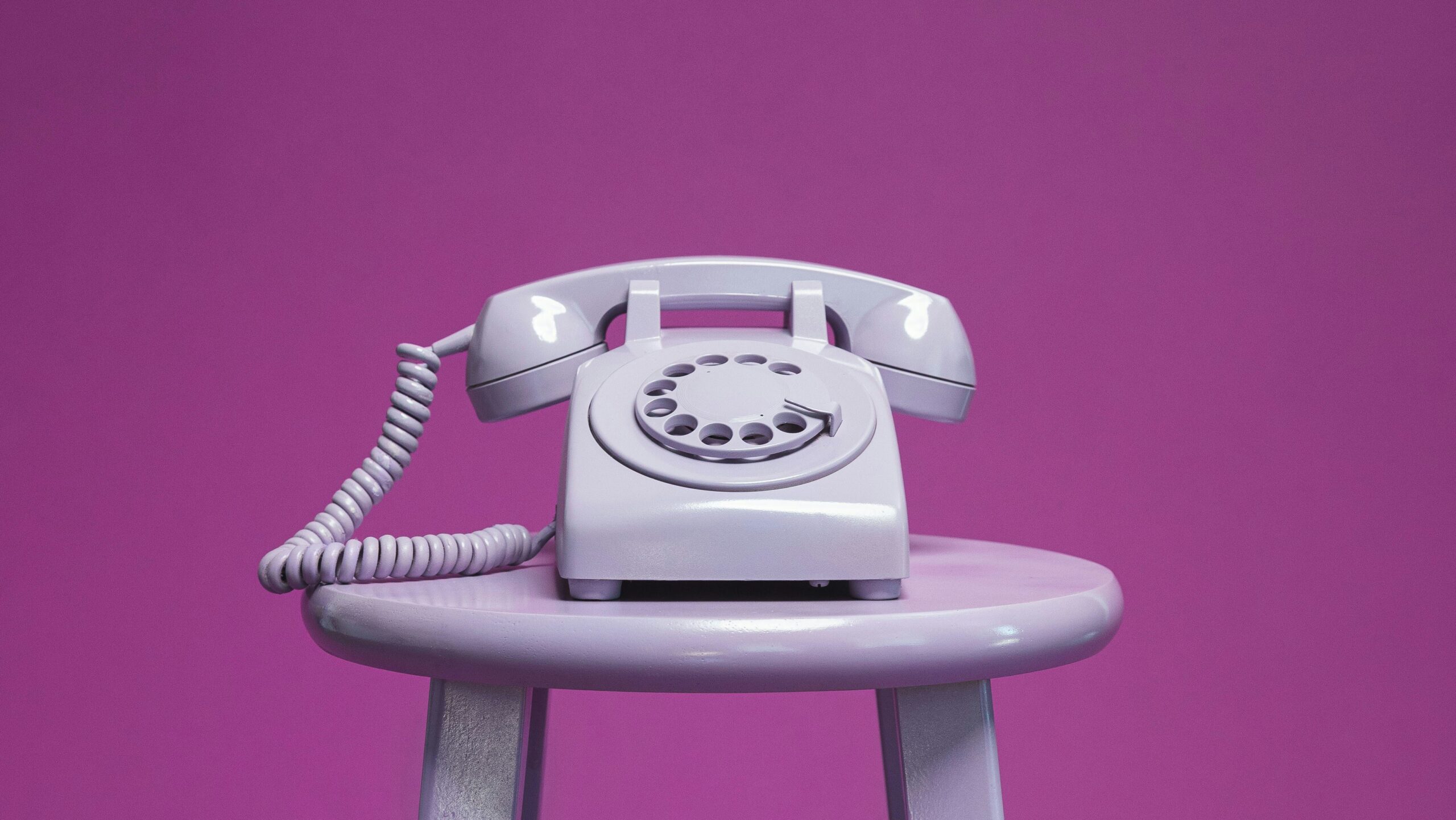 téléphone rétro posé sur un tabouret, sur fond violet